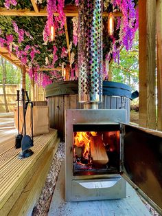 an outdoor wood burning stove with purple flowers on the ceiling and wooden decking around it