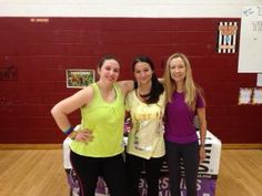 three women standing next to each other in a gym