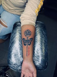 a woman's arm with a rose and butterfly tattoo on her left wrist, which reads love