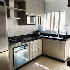 an empty kitchen with stainless steel appliances and black counter tops, along with white tile flooring