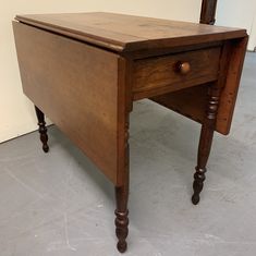 an old wooden desk with one drawer on the top and two turned down legs, in front of a mirror