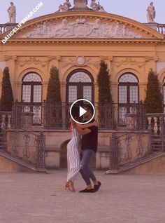 a man and woman dancing in front of a building