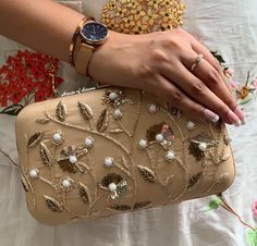 This is a beautiful handcrafted clutch bag made with love.It has intricate handwork which showcases the Indian craftsmanship by our local artisans. It comes with a metal sling chain. Details  - Single side handwork  - Fabric lining on the inside to keep your belongings safe  - Metal lock closure  - Detachable sling chain  This clutch can be worn as a crossbody bag or a shoulder bag with the sling chain or can simply be carried in hand.It is spacious enough to carry mobile phones, lipsticks, Keys and other small accessories. Dimension  Standard size - 8x4.5 inches  Please Note - Please message for base colour customisations. - Every clutch is handmade so sight colour/pattern variation might be there. Hand Embellished Potli Bag For Festivals, Hand Embellished Potli Bag For Festival Celebrations, Festive Embroidered Clutch Evening Bag, Glamorous Embellished Potli Bag For Festive Occasions, Glamorous Embellished Potli Bag For Festive Season, Glamorous Embellished Festive Potli Bag, Traditional Gold Clutch With Pearl Embroidery, Festive Embellished Potli Bag As Gift, Gold Zari Work Wedding Clutch