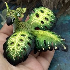 a hand holding a green and black bird figurine