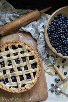 blueberries and pie sitting on top of a wooden cutting board