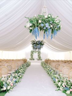 a wedding ceremony setup with chairs and flowers on the aisle in front of an open white tent