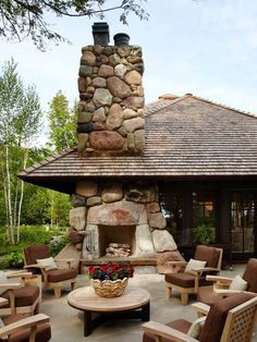 a patio with chairs, tables and a fire place in the center surrounded by rocks