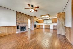 an empty living room with wood flooring and ceiling fan in the middle of it