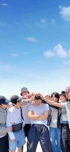 a group of young men standing next to each other in front of a blue sky