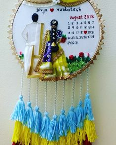 a wall hanging with a calendar and tassels attached to it's side