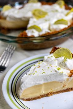 a slice of lemon pie on a plate with a fork and glass bowl in the background