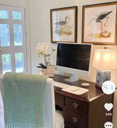 a desk with a computer on top of it next to a chair and pictures above the desk