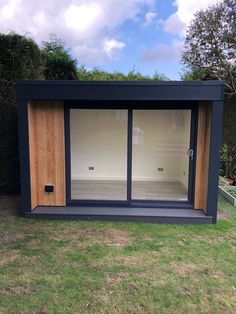 an outdoor sauna with sliding glass doors on the side and grass in front of it