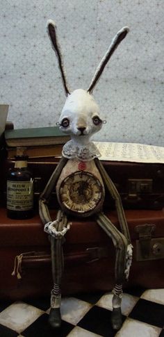 a rabbit figurine sitting on top of a pile of luggage next to a clock