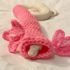 a crocheted pink object is laying on a white sheet with a toothbrush in it