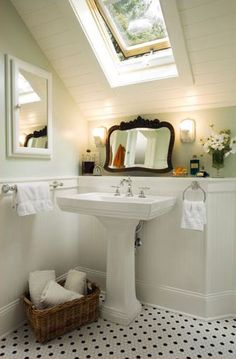 a white sink sitting under a bathroom mirror next to a window in a room with black and white tile flooring