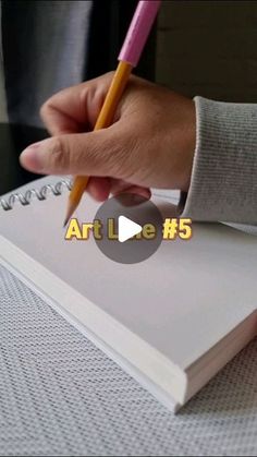 a person writing on a notebook with a pencil in their hand and the words art le 5 behind it