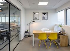 two yellow chairs sit at a desk in an office with glass walls and windows overlooking the city