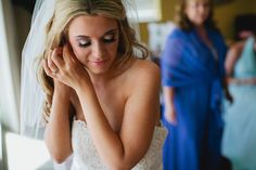 a woman in a wedding dress is looking down at her hand on her head while another woman stands behind her