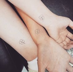 two people with tattoos on their legs holding each other's hands and one has four leaf clovers