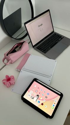 an open laptop computer sitting on top of a white desk next to a pink purse