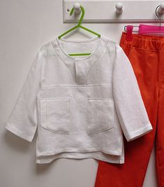 two children's clothing hanging on a clothesline next to a pair of red pants