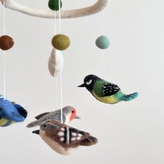 three birds are hanging from a mobile made out of felt balls and wool yarns