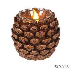 a small pine cone candle holder with a lit candle in the center, on a white background