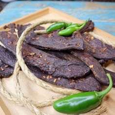 sliced beef and peppers on a wooden cutting board with twine around the edges for garnishes