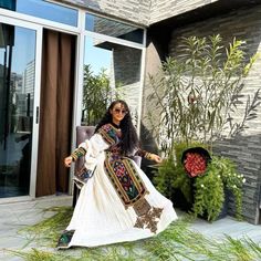 a woman sitting on a chair in front of a building with plants and potted plants