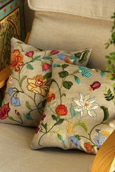 two decorative pillows sitting on top of a chair