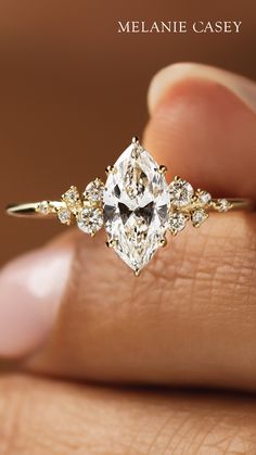 a woman's hand holding an engagement ring with a diamond in the center and two diamonds on each side