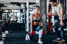 a man and woman doing squats with dumbbells in a gym together,