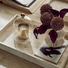 a vase filled with purple flowers sitting on top of a table next to an open book