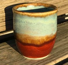 a coffee cup sitting on top of a wooden bench