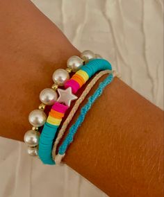 a close up of a person's arm wearing bracelets with pearls and beads