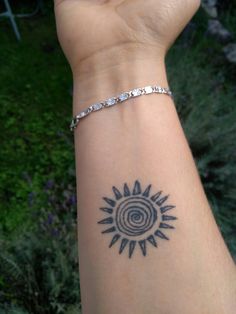 a woman's arm with a tattoo on it and a spiral design in the middle