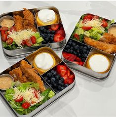 three tins filled with different types of food on top of a white countertop