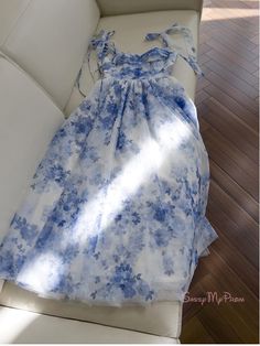 Regal and refined, this blue floral homecoming dress is a stunning choice for any special occasion. The dress is adorned with a delicate blue floral print that is both classic and contemporary, creating a look that is as elegant as it is fresh. The bodice features ruched detailing that enhances the bust and adds texture, while the off-the-shoulder straps with charming bow accents provide a feminine and romantic touch. The waist is cinched with a slender tie, allowing the full skirt to drape beau Chic Floral Print Dresses For Prom Season, Floral Print Midi Dress For Prom, Feminine Floral Print Prom Dress, Light Blue Sleeveless Floral Print Dress, Light Blue Floral Print Sleeveless Dress, Spring Prom Chiffon Midi Dress, Light Blue Floral Print Wedding Dress, Blue Floral Print Dress With Sweetheart Neckline, Fitted Floral Print Dress For Prom