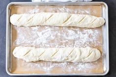 two loaves of bread sitting on top of a baking pan next to a baguette