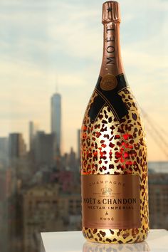 a bottle of champagne sitting on top of a table next to a cityscape