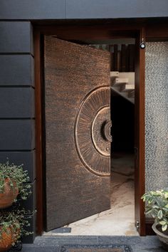 an open door to a building with potted plants