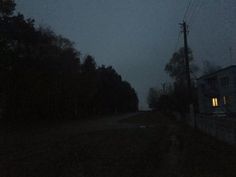 an empty road at night with the lights on and trees in the dark behind it