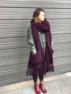 a woman standing in front of a garage door wearing a purple scarf and red boots