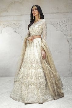 Off White Lehenga Choli Dupatta Pakistani Dress in pure organza fabric is a stunning choice for the Bride. This breathtaking Bridal Lehenga Choli is emblazoned with lavish designs and fine details. Classic embellishments give a glamorous touch to this perfectly stitched Lehenga Choli. Choli: Beautiful choli in the off-white shade is hand-embellished with pearls, stones, motifs, and sequins. The stylish neckline and adorned sleeves give a royal touch to this perfectly stitched choli. Beads and si Off White Lehenga, White Lehenga Choli, Latest Pakistani Dresses, White Lehenga, Pakistani Dresses Online, Lehenga Online, Maria B, Pakistani Dress, Bridal Lehenga Choli