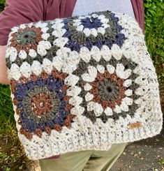 a person is holding a crocheted square in their hands