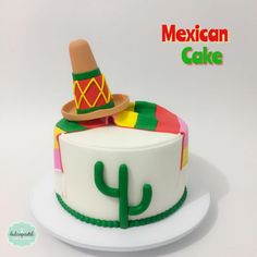 a mexican themed cake with a hat and cactus on top, sitting on a white plate