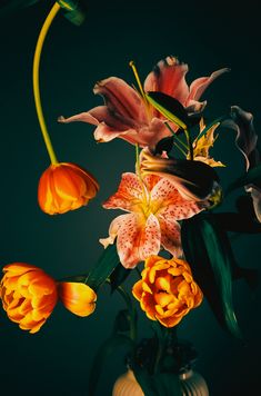 a vase filled with lots of flowers on top of a wooden table in front of a dark background