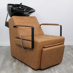 a brown reclining chair sitting on top of a hard wood floor next to a white wall