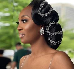 a woman with black hair wearing a white dress and some silver jewelry on her head